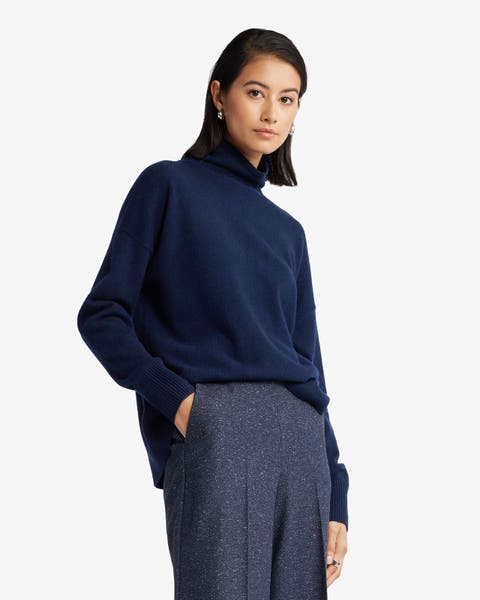 Woman wearing a navy turtleneck sweater with dark blue wide‑leg trousers.