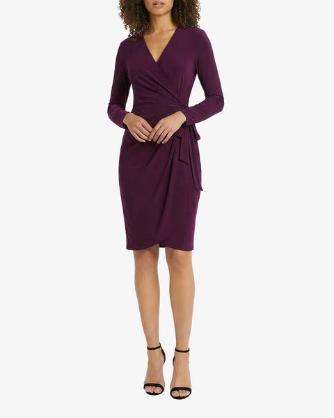 Model wearing a deep purple long-sleeve wrap dress with black strappy heels.