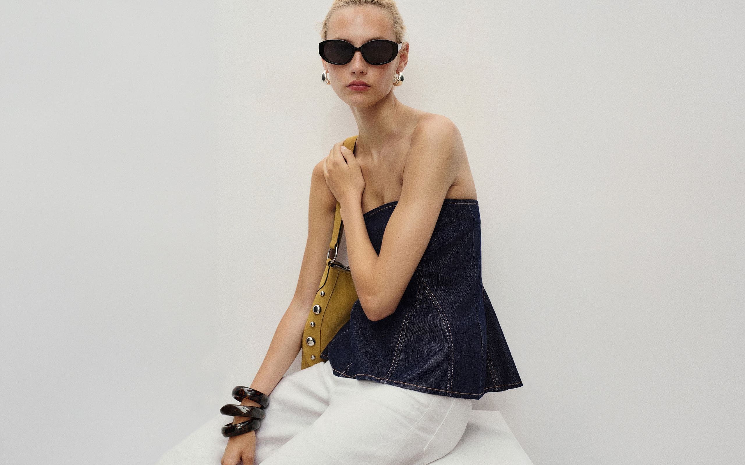 A woman wearing a strapless flare-hem denim top.