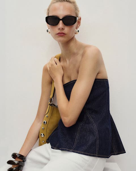 A woman wearing a strapless flare-hem denim top.