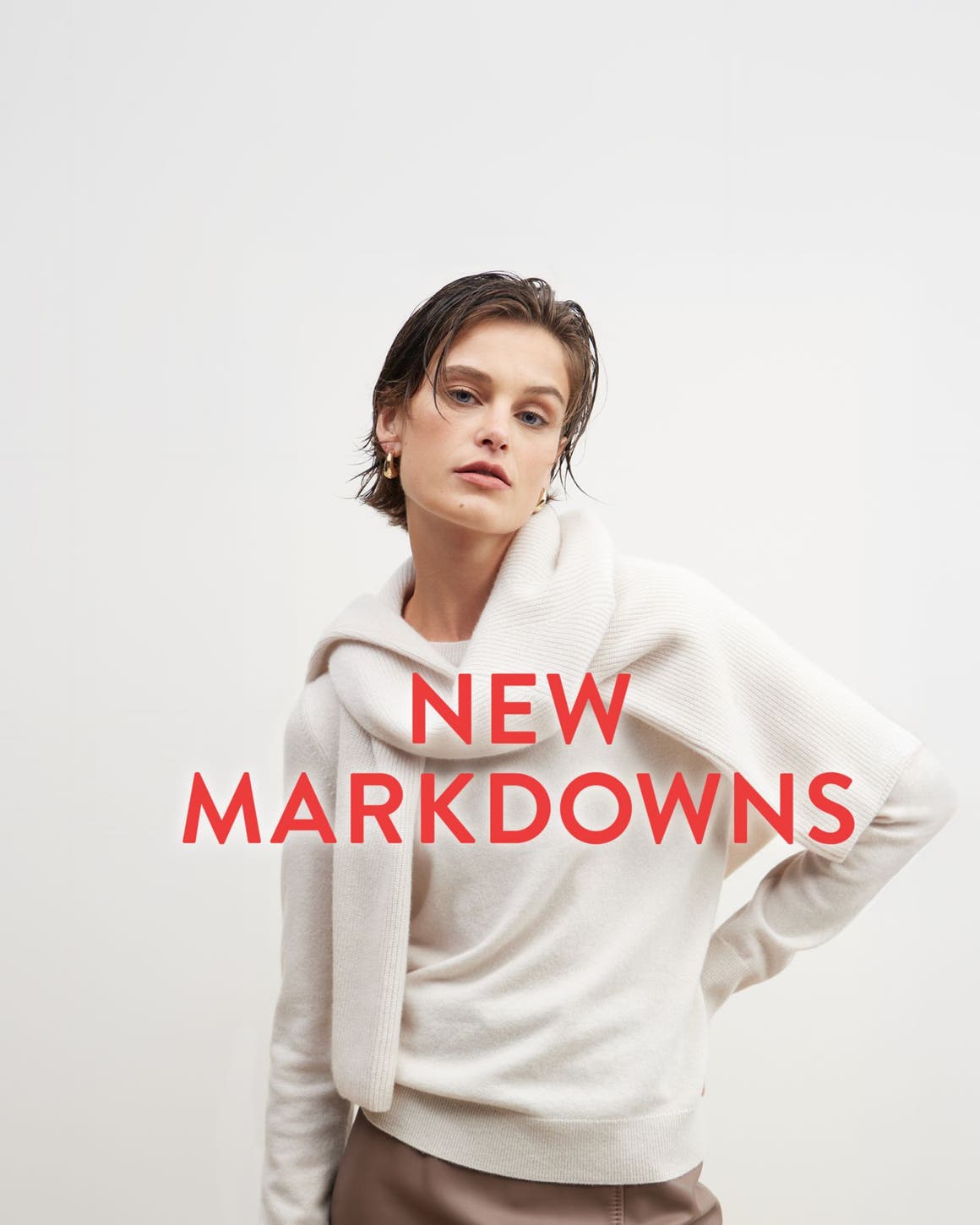 New markdowns: a woman in a beige sweater with another sweater tied around her shoulders.