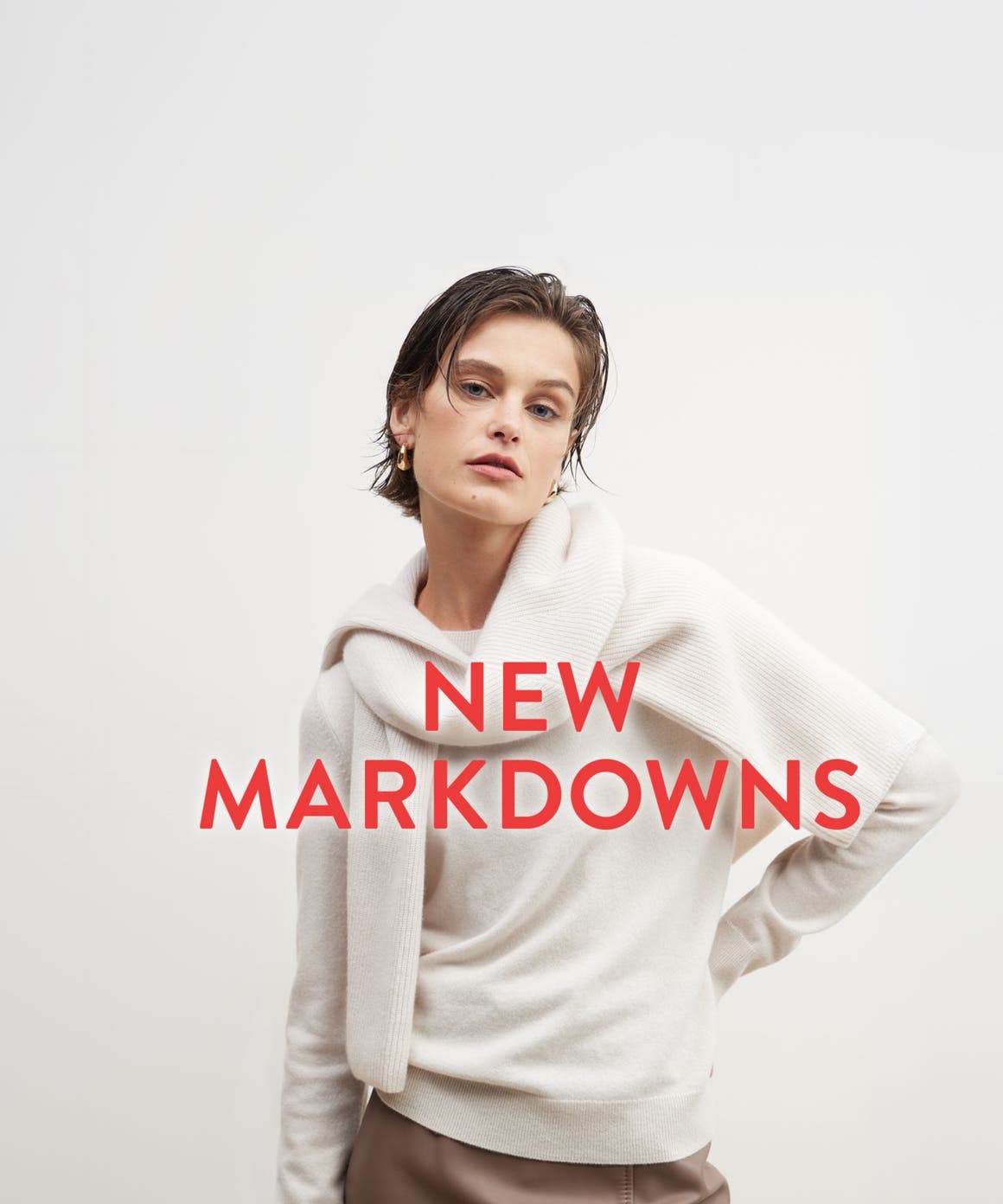 New markdowns: a woman in a beige sweater with another sweater tied around her shoulders.