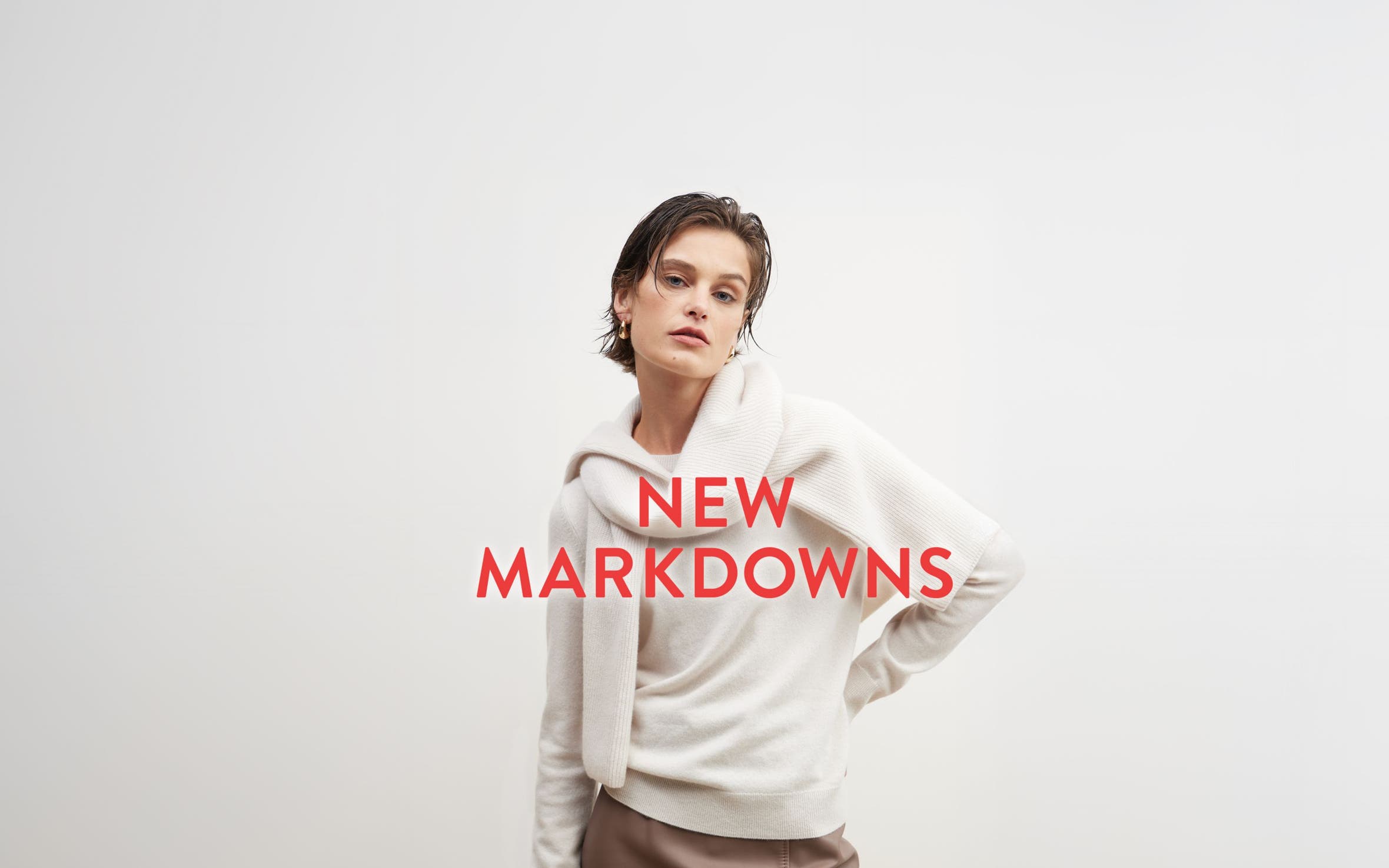 New markdowns: a woman in a beige sweater with another sweater tied around her shoulders.