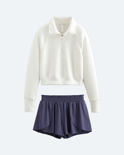 A white quarter-zip sweatshirt and grey, blue running shorts.