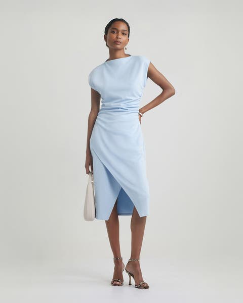 Woman wearing a light blue dress and strappy heels.