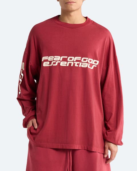 A man wearing a long-sleeve logo T-shirt from Fear of God Essentials.