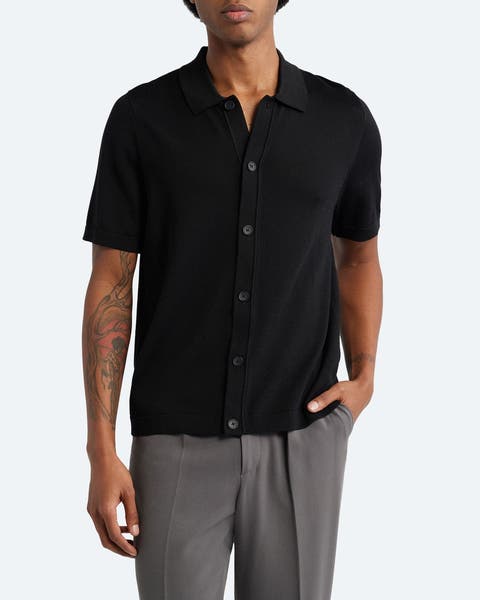 A man wearing a short-sleeve, black, button-front sweater.