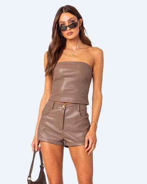 A woman wearing brown leather shorts and a matching top. 