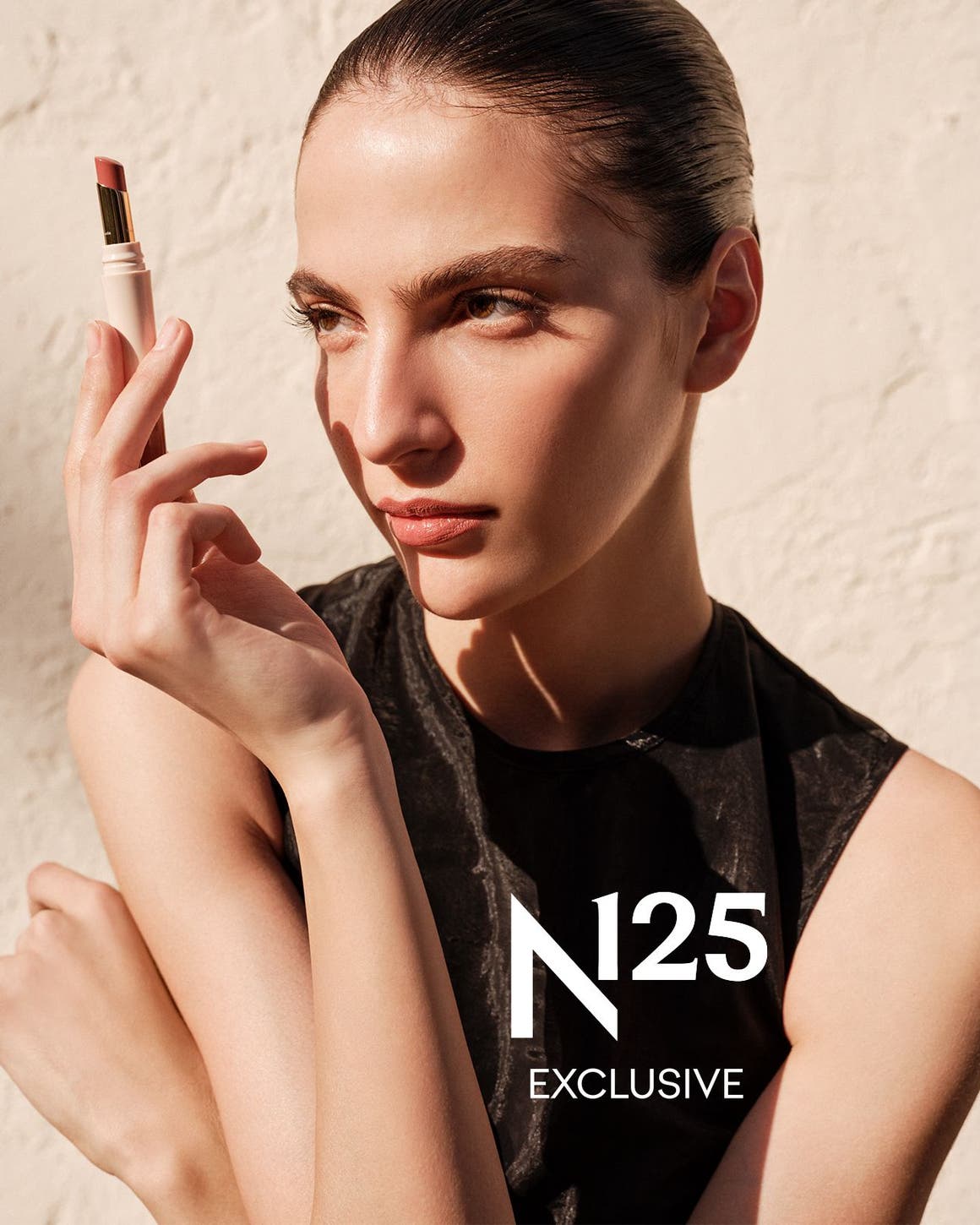 A woman holding a tube of lipstick.