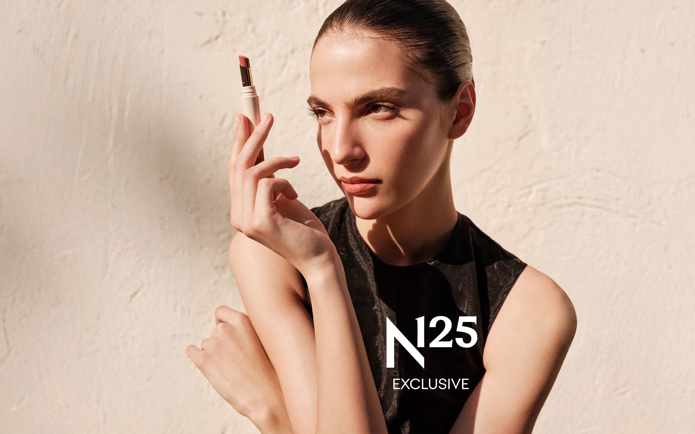 A woman holding a tube of lipstick.