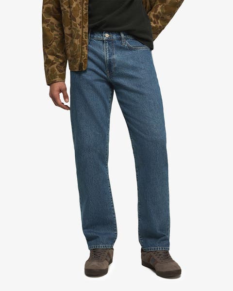 Straight-leg medium-wash jeans styled with a camo jacket and brown sneakers.