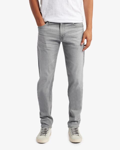 Slim light gray jeans styled with a white tee and cream sneakers.