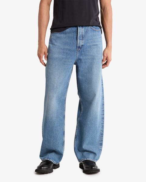 Baggy light-wash jeans styled with a black tee and black loafers.