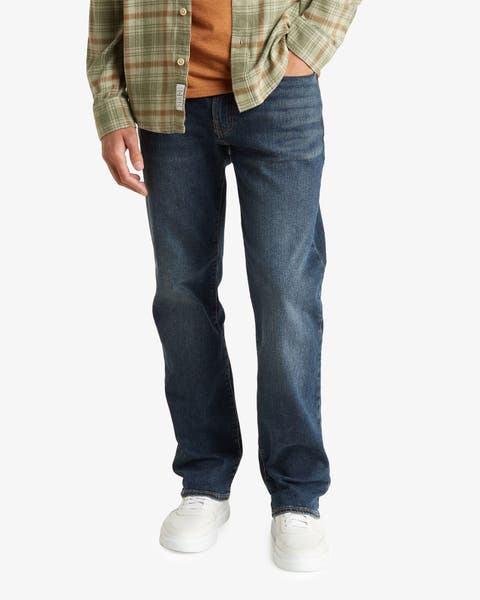 Dark-wash straight-leg jeans styled with a plaid shirt and white sneakers.