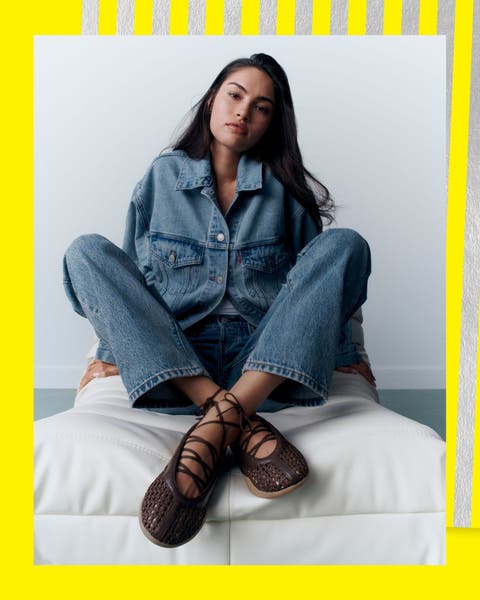 A woman wearing lace-up sneakers with a denim outfit.