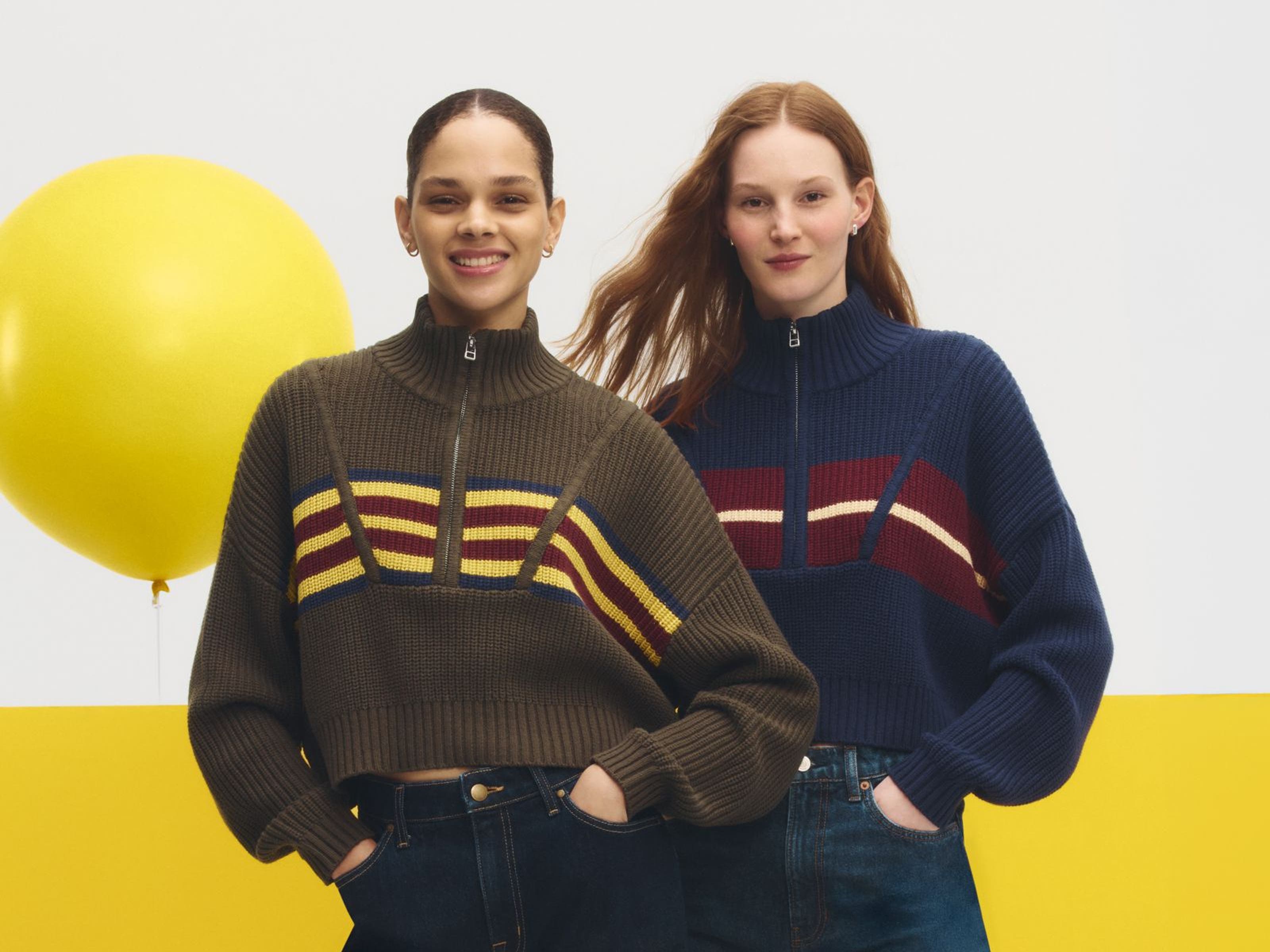 Two women wearing sweaters & jeans.