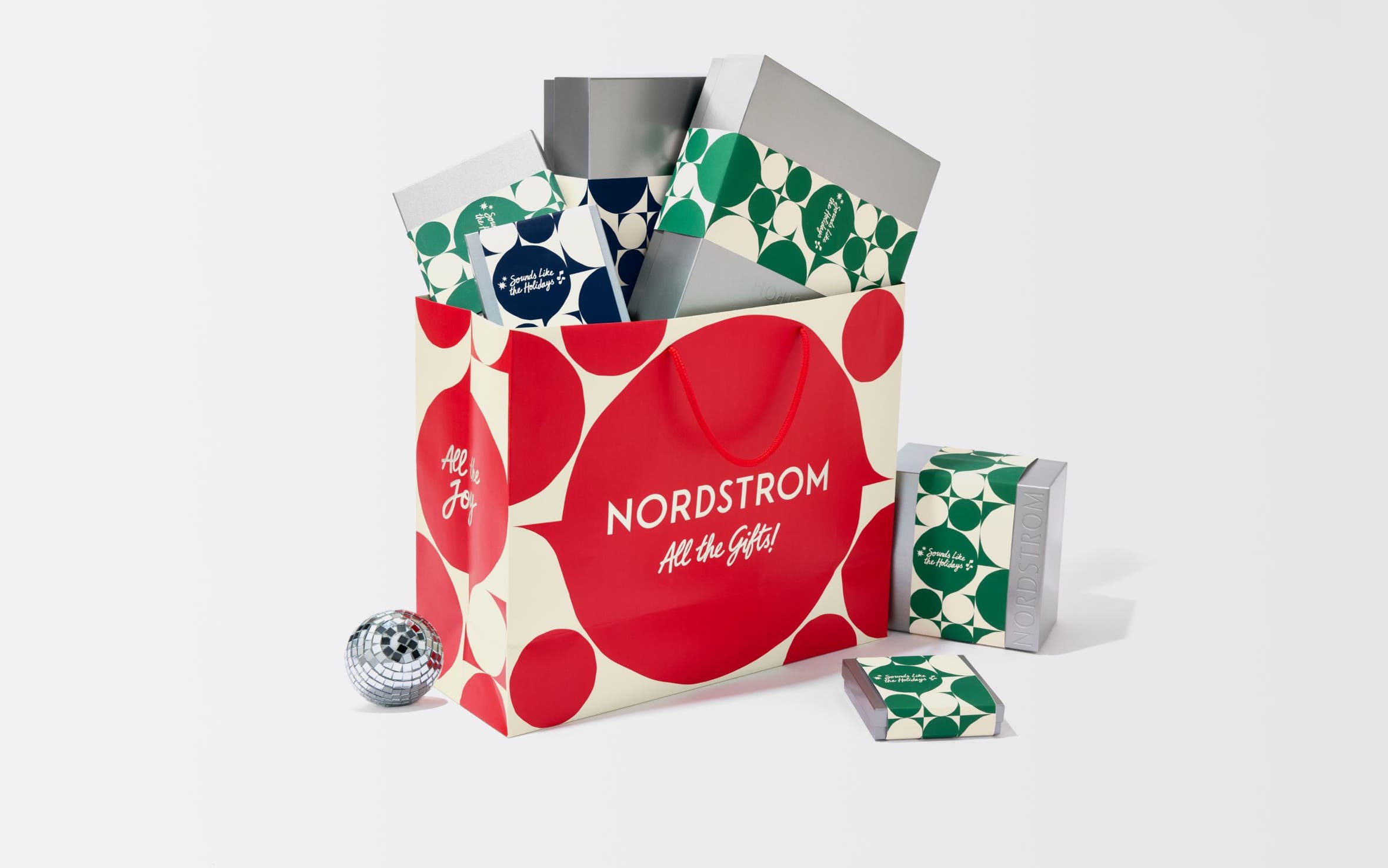 A red Nordstrom shopping bag with silver gift boxes.