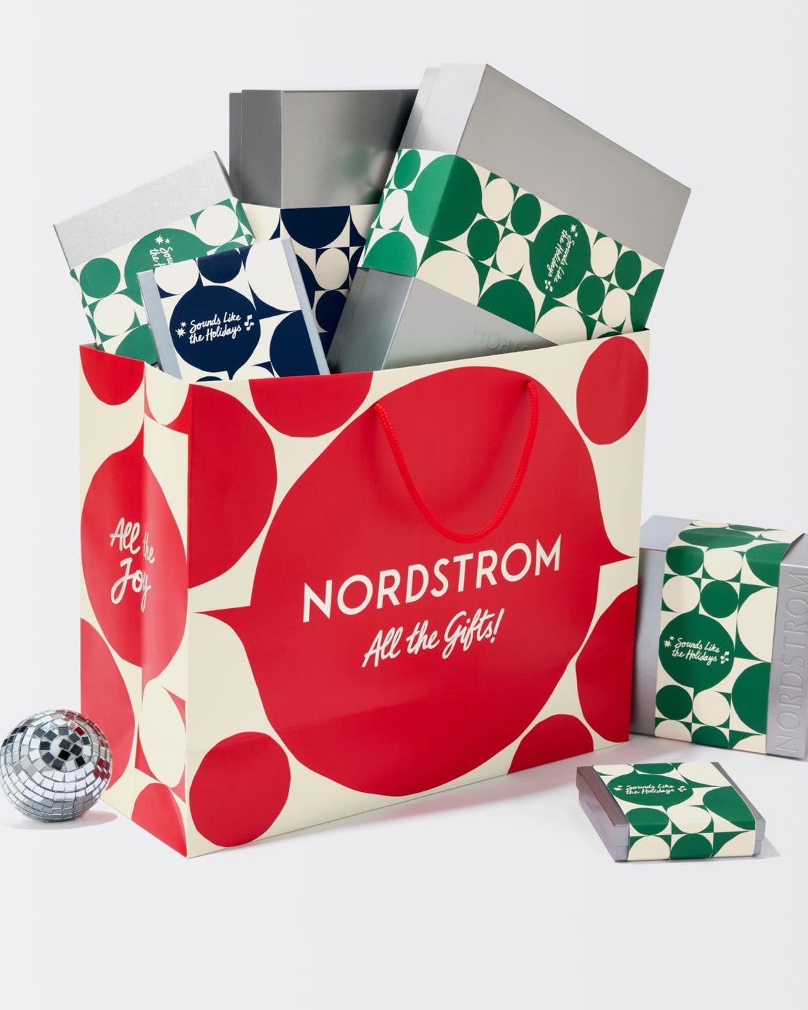 A red Nordstrom shopping bag with silver gift boxes.