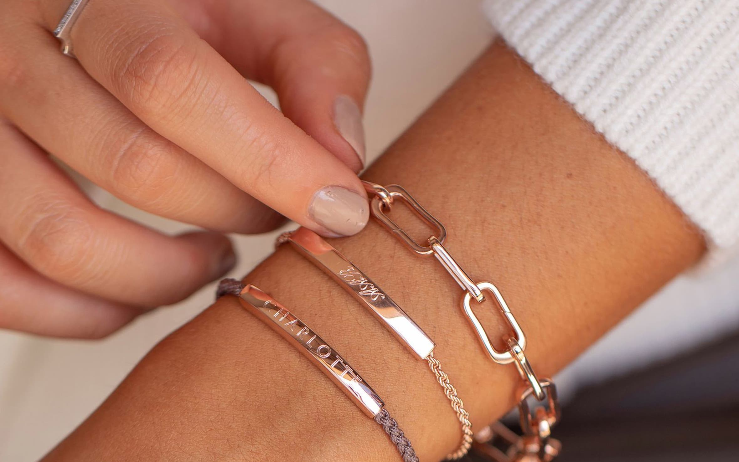 A woman wearing a stack of personalized jewelry. 