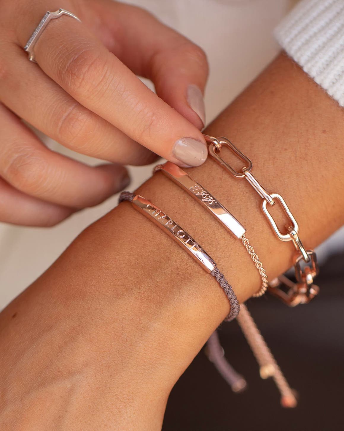 A woman wearing a stack of personalized jewelry. 