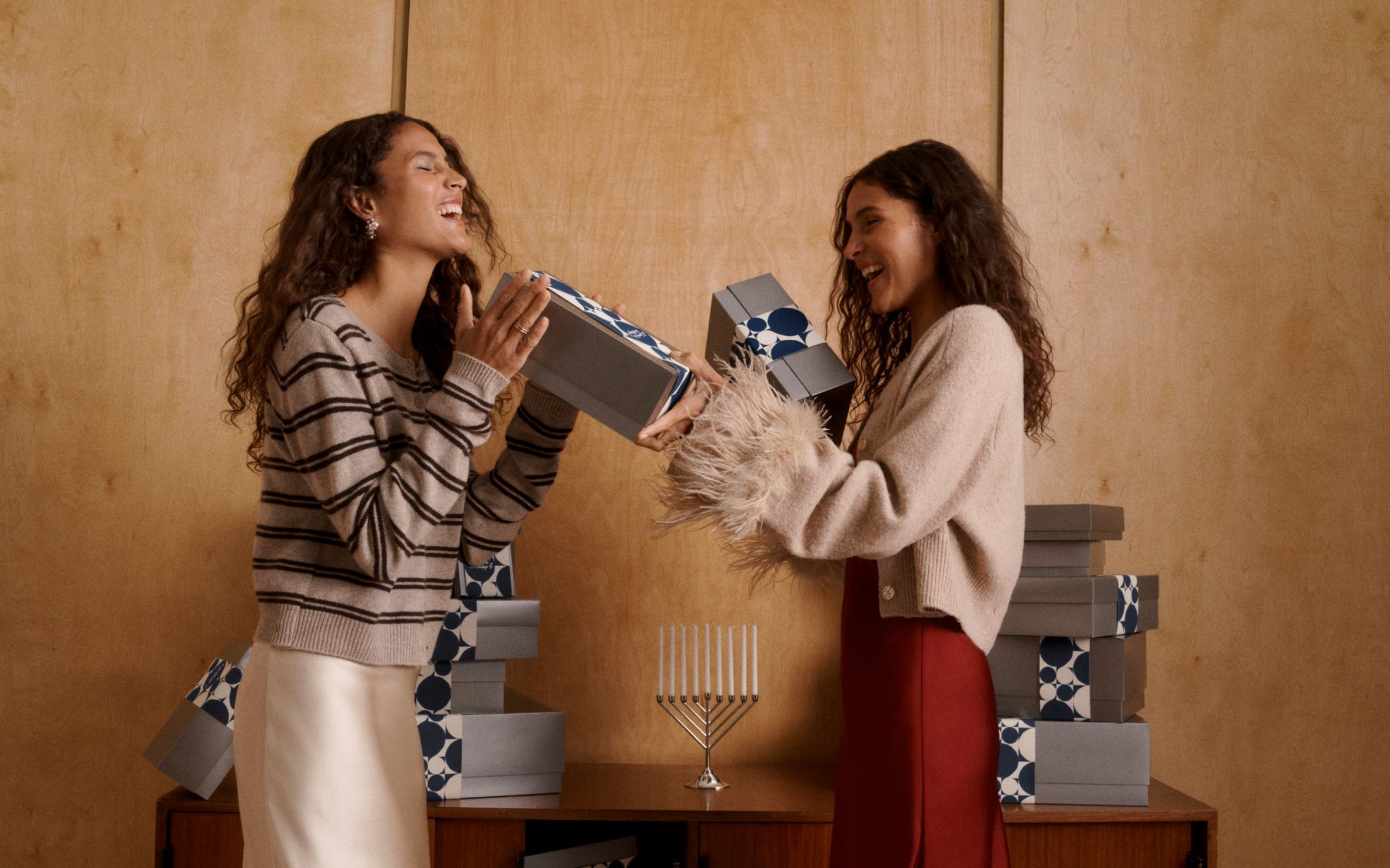 Two women exchanging silver Nordstrom gift boxes. 