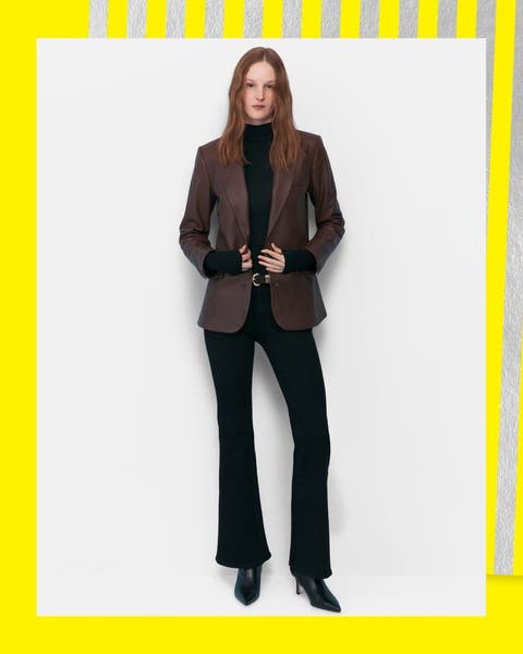 A woman wearing a leather blazer and bootcut jeans.