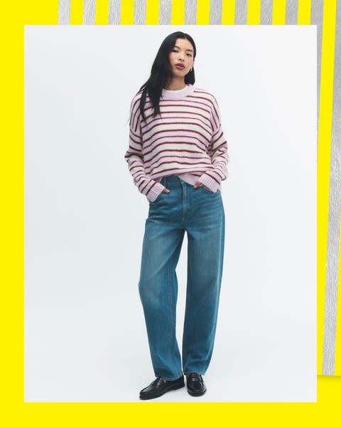 A woman wearing a striped long sleeve and barrel jeans.