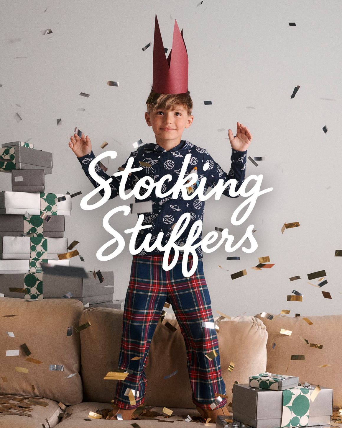 Stocking stuffers. A boy surrounded by confetti and a stack of gifts.
