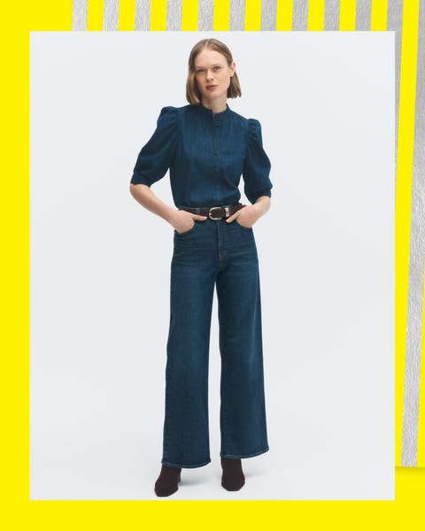A woman wearing a navy blouse and high waist jeans.