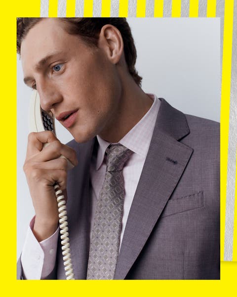 A man in a light grey suit and a light grey patterned silk tie.