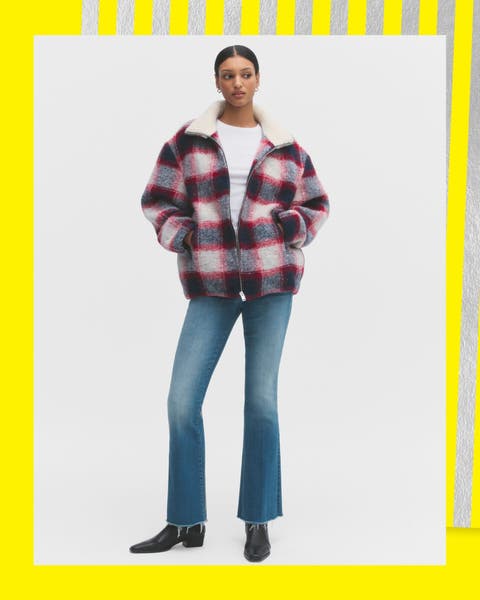 A woman wearing a flannel jacket and ankle flare leg jeans.