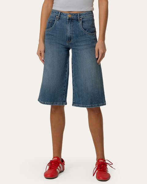 A woman wearing a pair of long denim shorts.