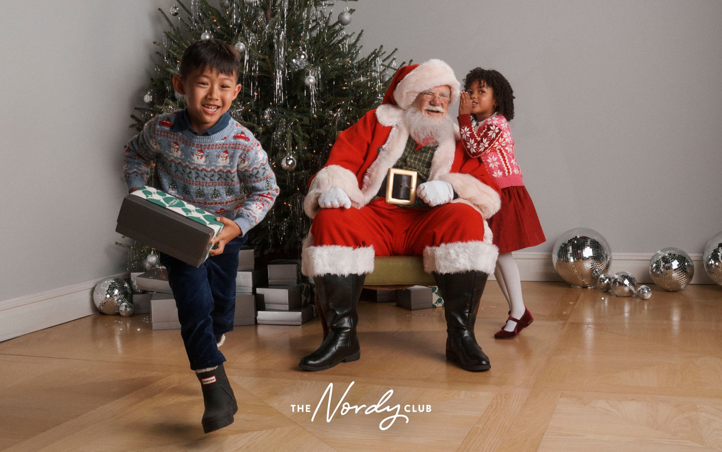Santa with two children around a Christmas tree.