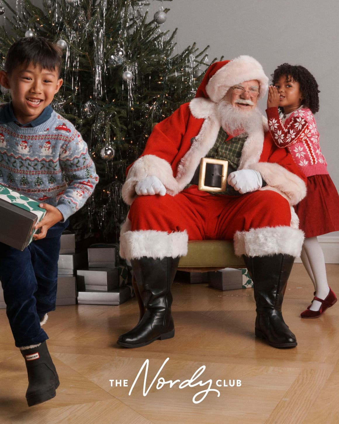 Santa with two children around a Christmas tree.