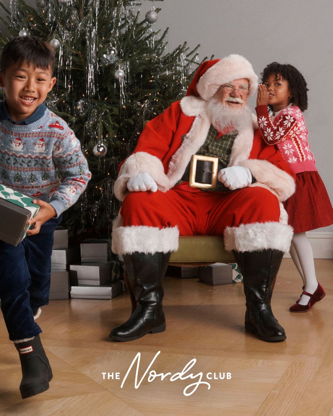 Santa with two children around a Christmas tree.