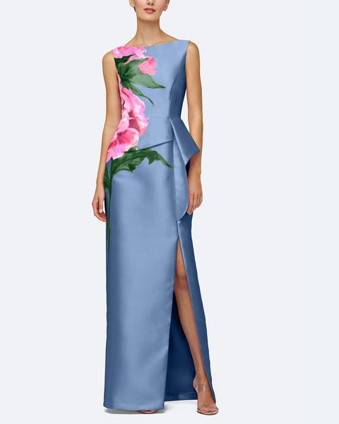 A woman wearing a blue gown with side ruffle and pink flower pattern.