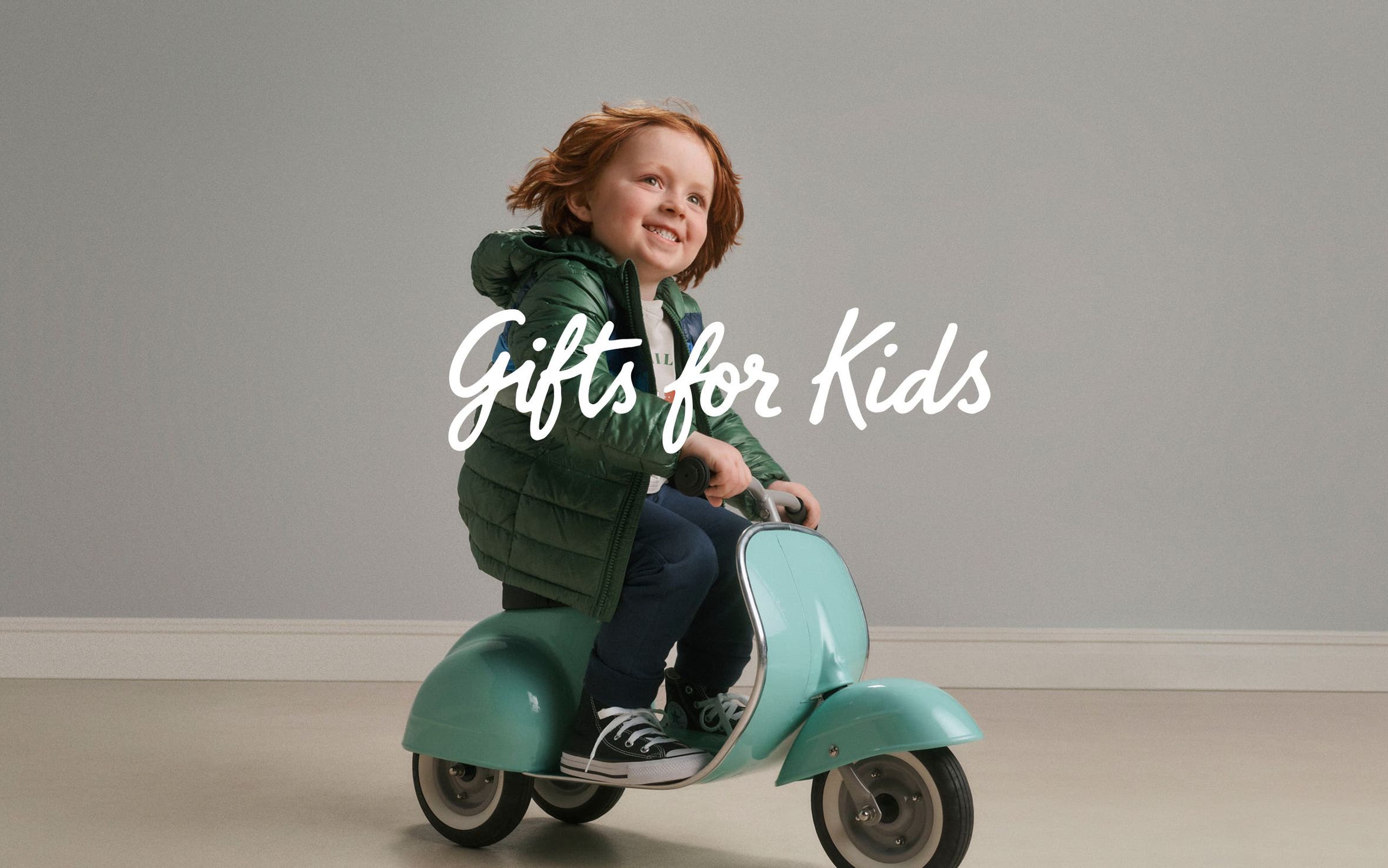 Gifts for kids. A kid riding a toy scooter.