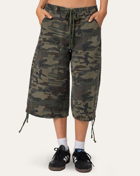 A woman wearing long, camo cargo shorts.