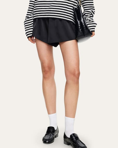 A woman wearing black satin mini shorts.