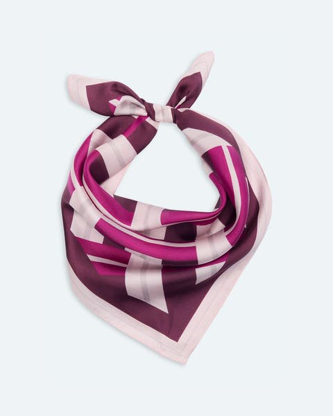 Purple, magenta, and white geometric-print silk scarf tied in a bow.