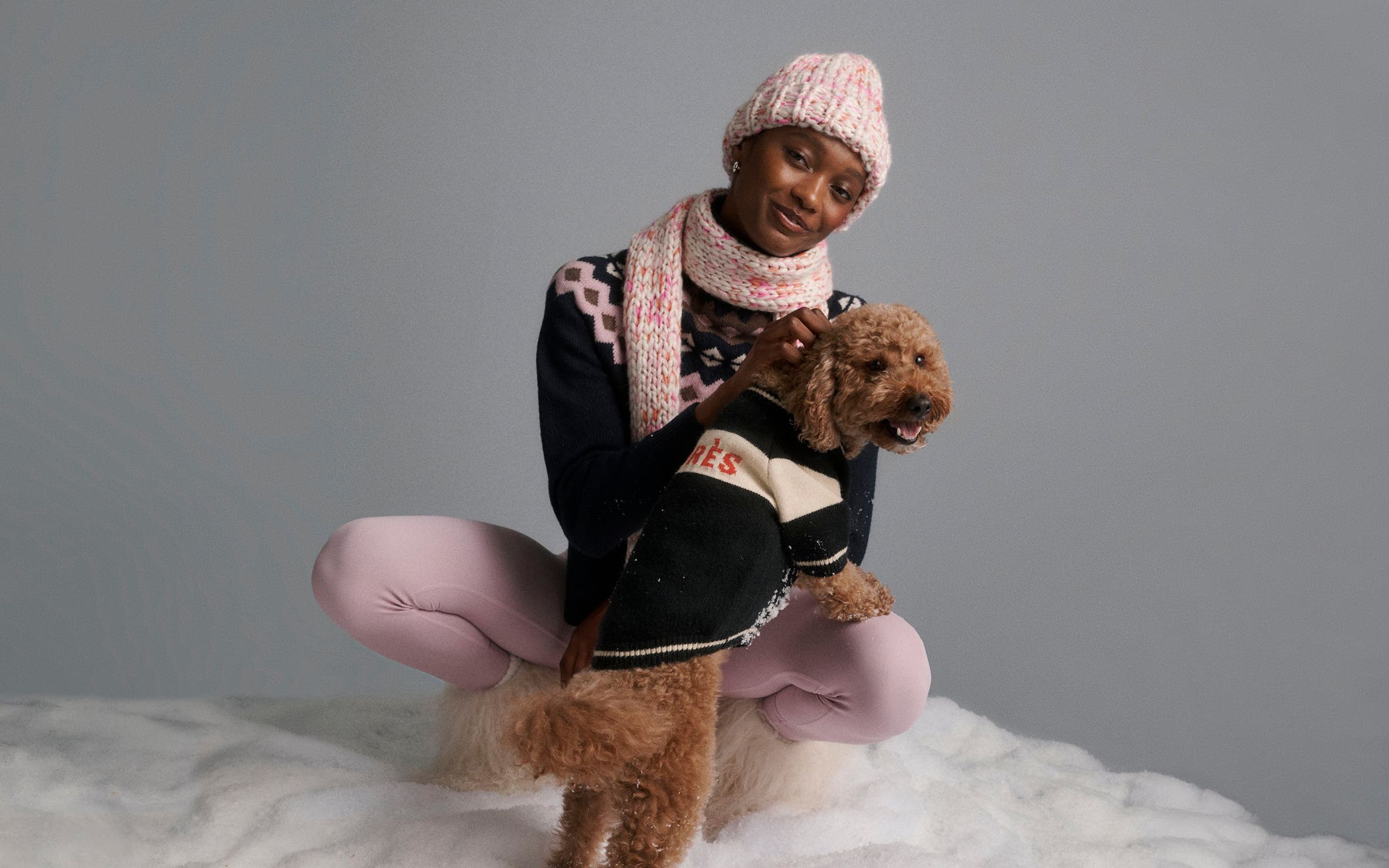 A woman with a dog in a sweater.