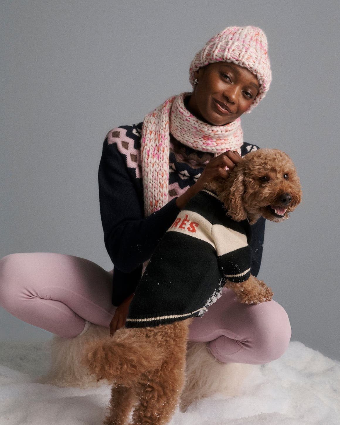 A woman with a dog in a sweater.