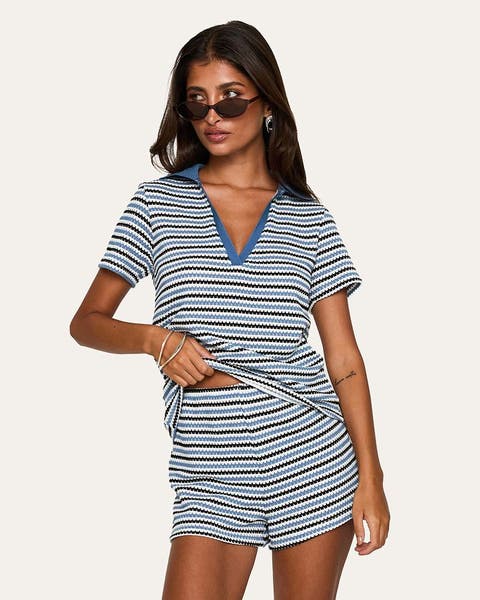A woman wearing a striped polo and matching mini shorts.