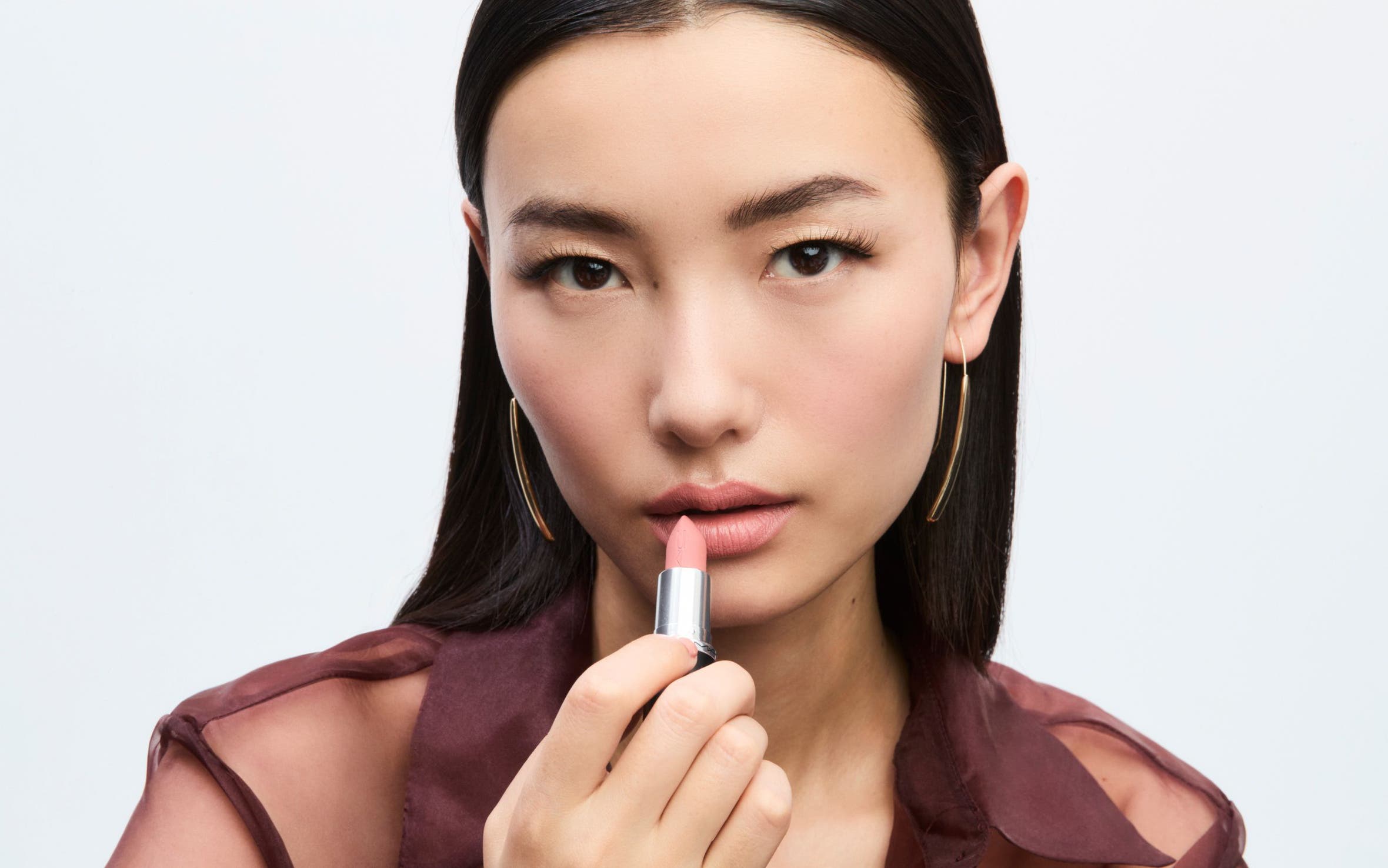 A woman applying MAC Cosmetics lipstick.