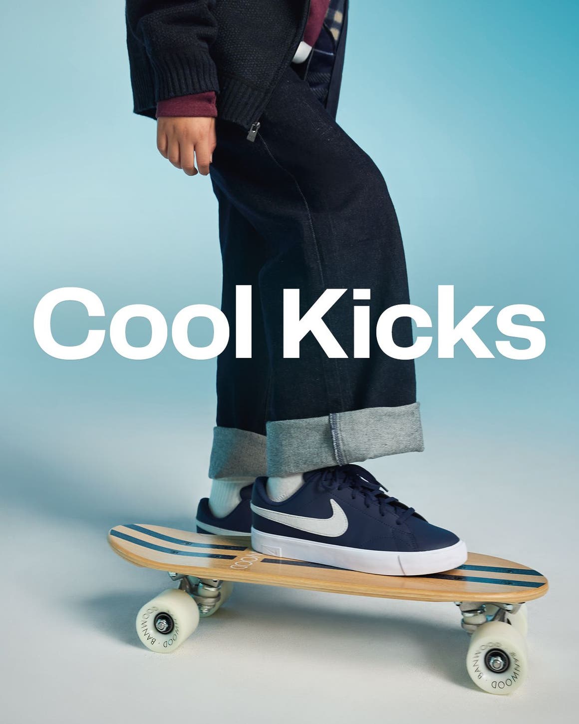 Cool kicks. A kid wearing Nike sneakers stands on a skateboard.  