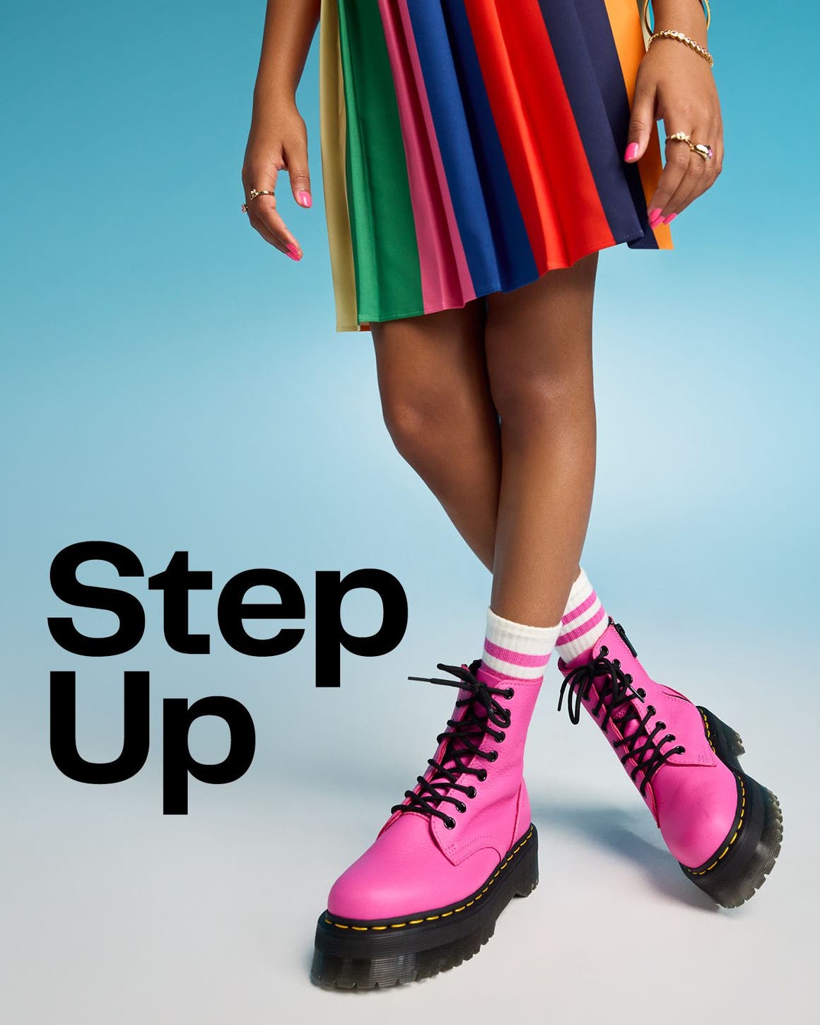 Step up. A young girl wearing a rainbow-colored skirt with pink combat boots.  
