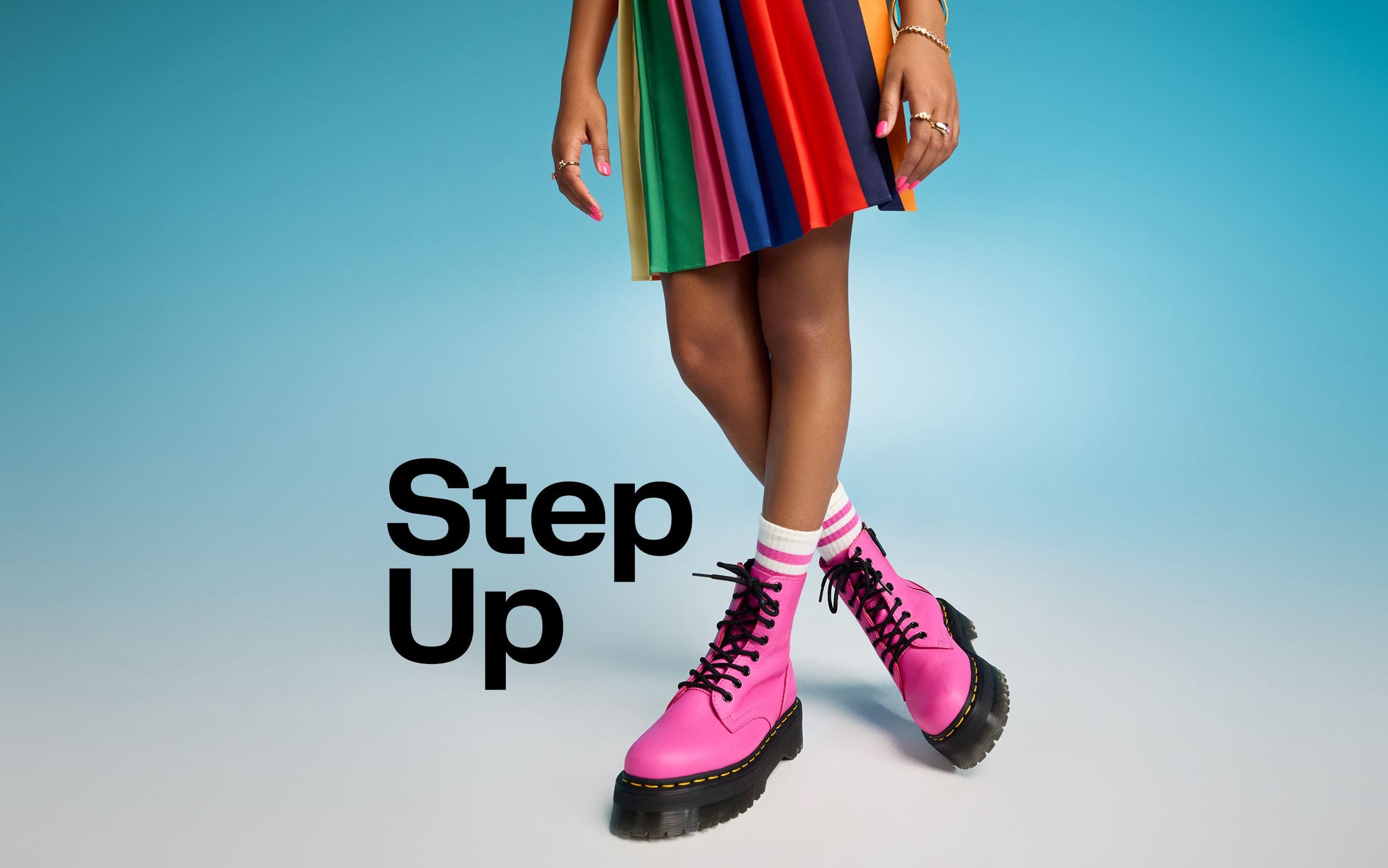 Step up. A young girl wearing a rainbow-colored skirt with pink combat boots.  