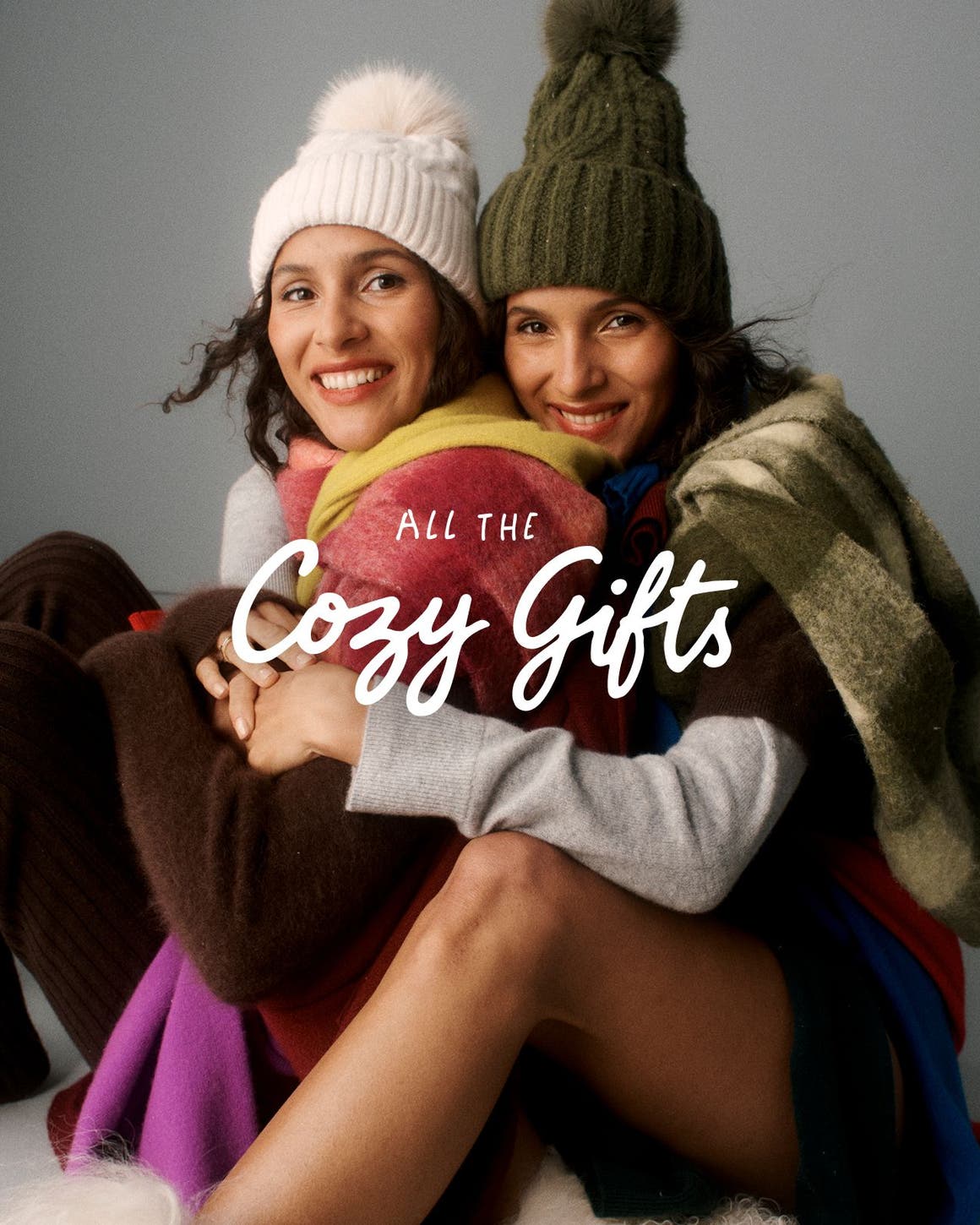 All the cozy gifts. Two women wearing cashmere; a stack of sweaters.