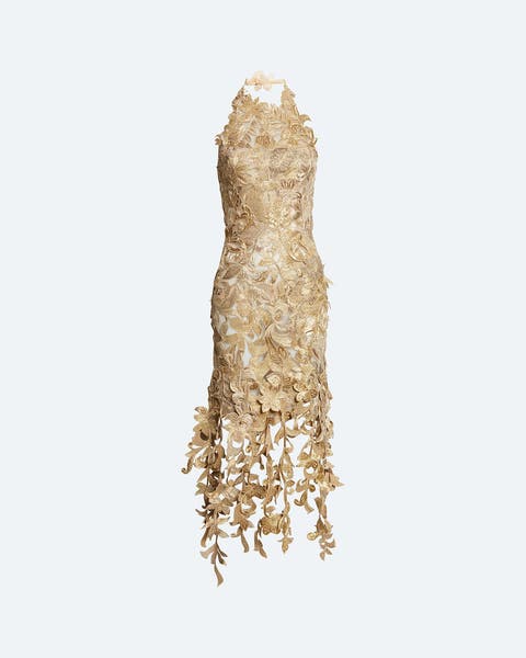 Sleeveless midi dress in a metallic gold color, covered in dimensional floral and leaf-shaped appliqués, with a fringe-like hem of hanging petal and vine details, shown on a mannequin against a plain background