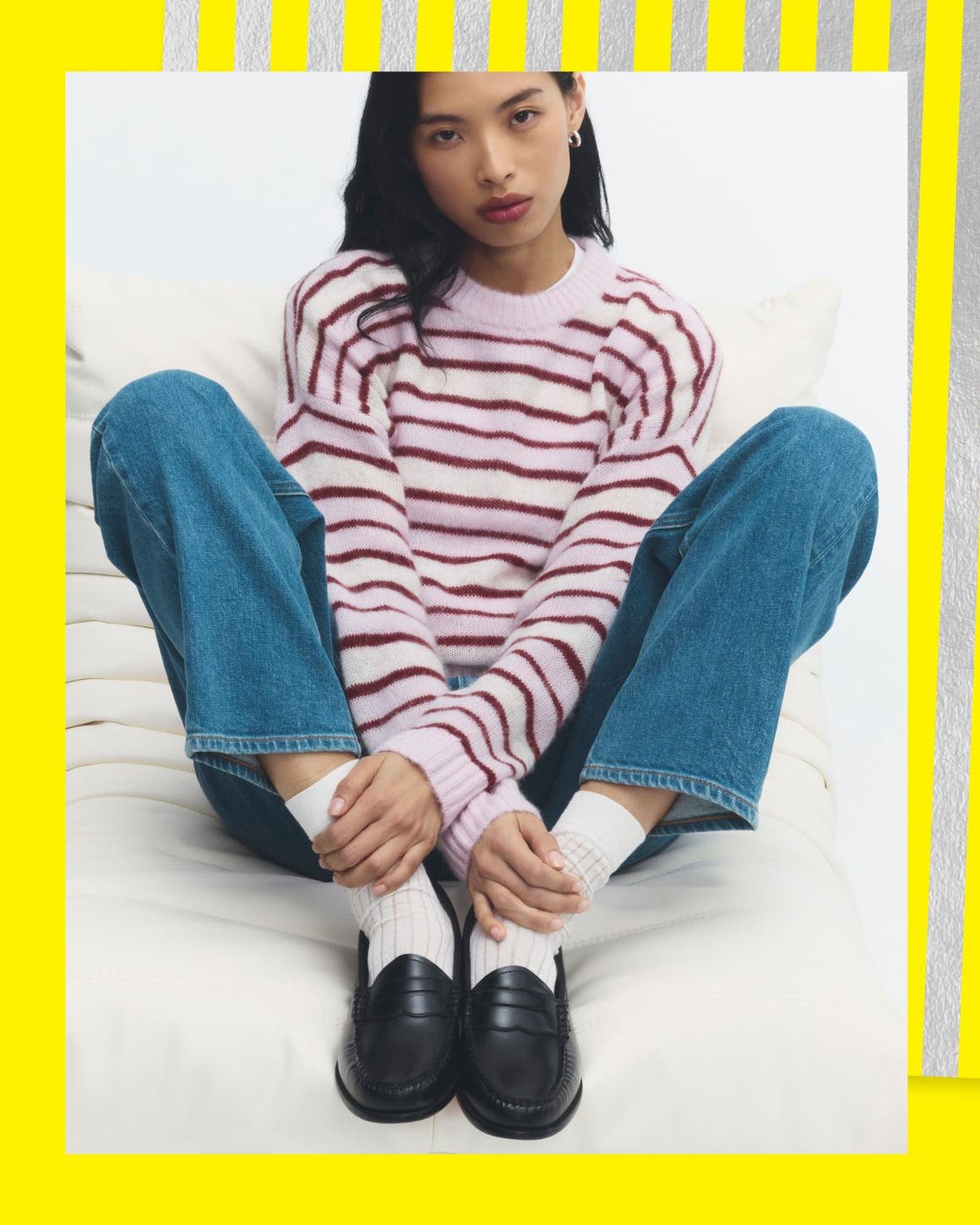 A woman in a striped shirt, jeans and dark leather loafers.